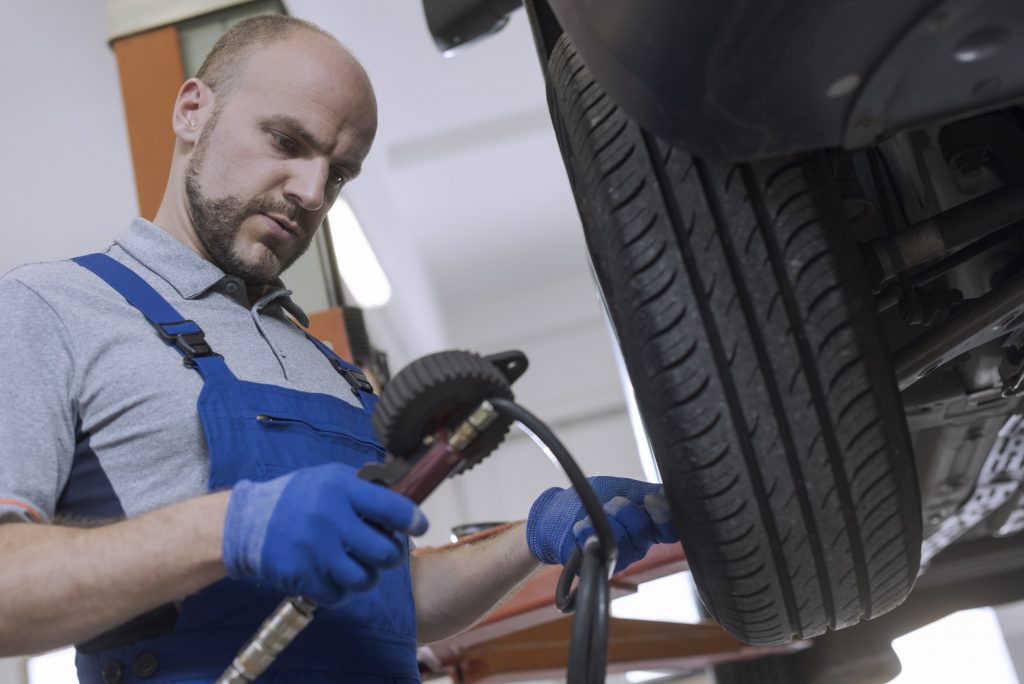 Mechanic inflating a tire and checking air pressure with a pressure gauge