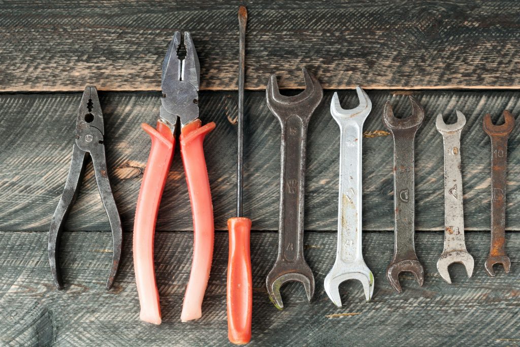 Old wrenches and pliers on wooden background. Set of tools. Top view